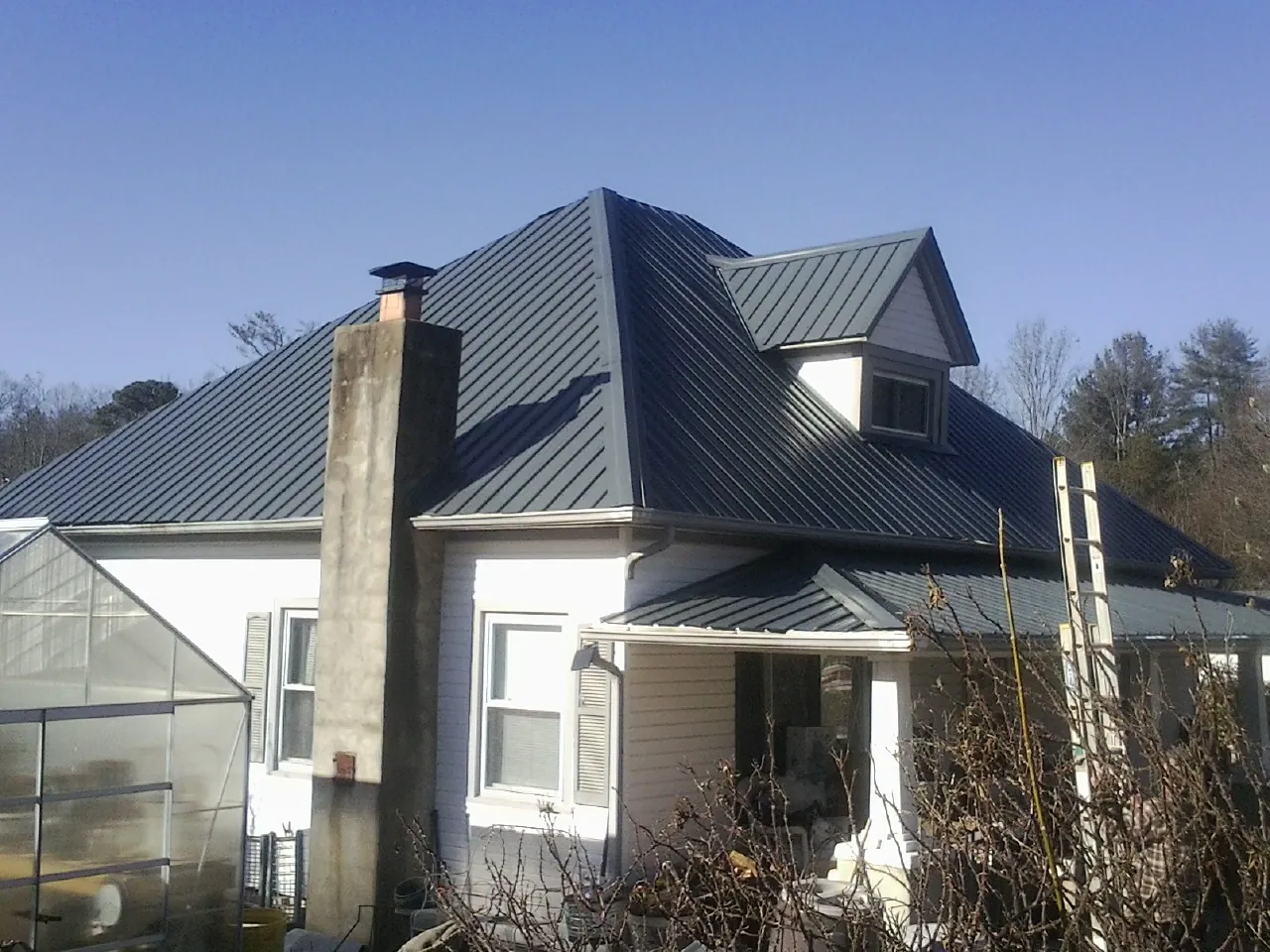 Dark blue standing seam metal roof on a white farmhouse with dormer — Slate & Tile Roof Repair by Roofing Brothers in Orderville