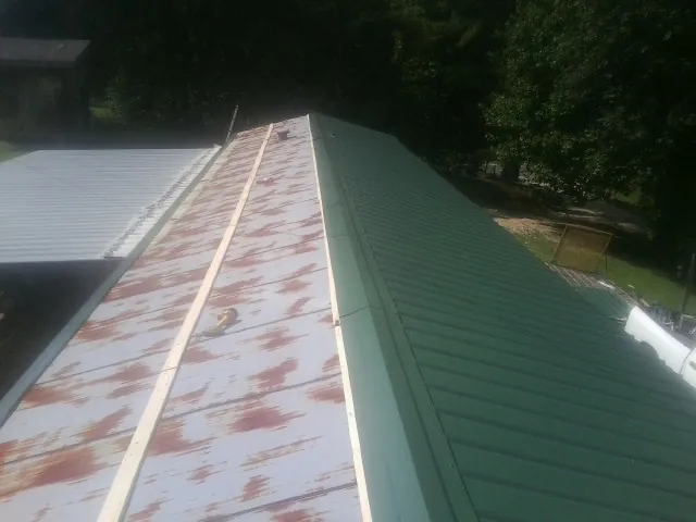 Old rusted panels beside newly installed green metal roofing — Wind Damage Roof Repair by Roofing Brothers in Orderville