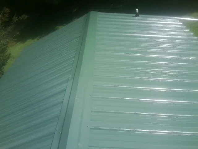 New green metal panels meeting at the ridge of a roof — Flat Roof Repair work by our crew in Orderville