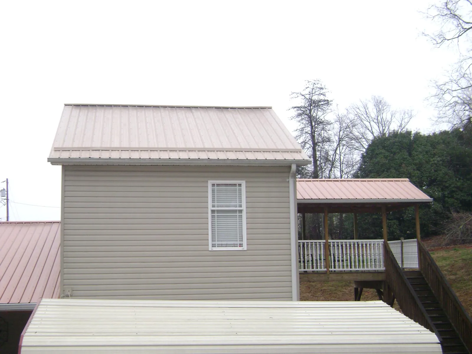 Tan metal roofs on a two story addition and attached porch, from a Roof Replacement job in Orderville