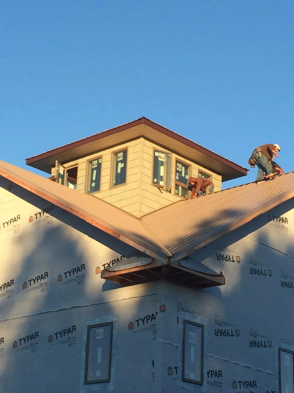 Roofers working around a rooftop cupola on a new metal roof at sunset — Roof Waterproofing in Orderville by Roofing Brothers